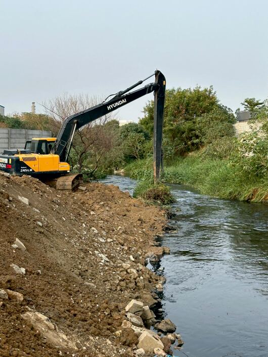 Excavator performing mass excavation works beside a water canal in Bengaluru