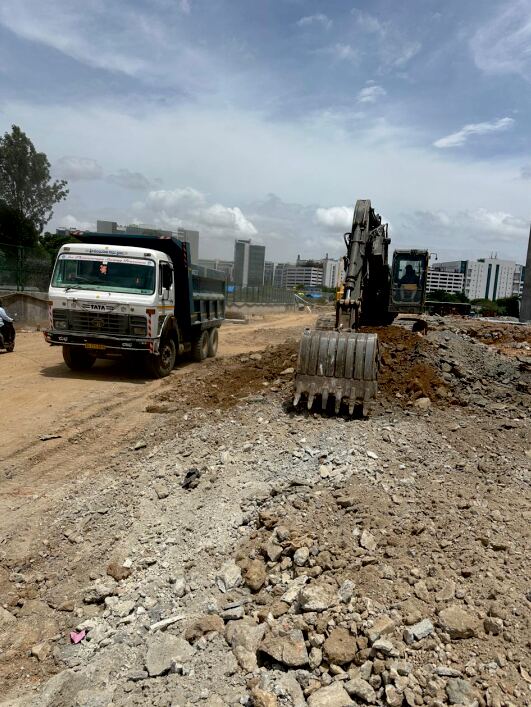 Excavator and dump truck performing mass excavation on a road site in Bengaluru